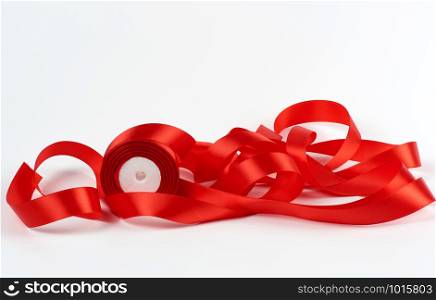 curled red satin ribbon on white background, festive backdrop, close up