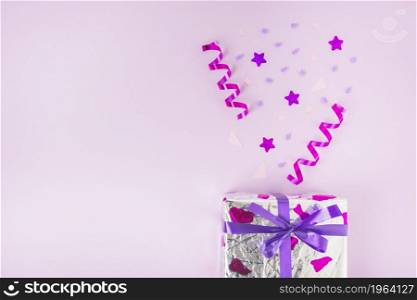curled streamers star shape confetti silver gift box against pink background. High resolution photo. curled streamers star shape confetti silver gift box against pink background. High quality photo
