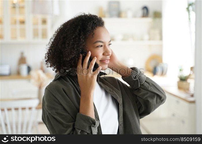 Curly afro girl has phone call at kitchen at home and listening to friend. Young african american woman is talking to friends, remote conversation. Communication technologies, electronic gadgets.. Curly afro girl has phone call at kitchen at home and listening to friend. Remote conversation.