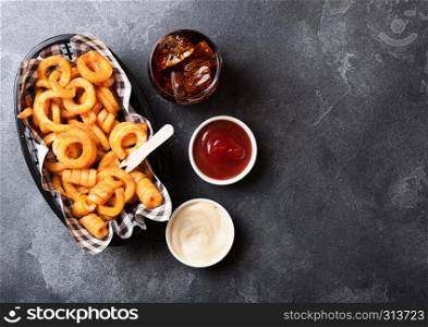 Curly fries fast food snack in red plastic tray with glass of cola and ketchup on kitchen background. Unhealthy junk food