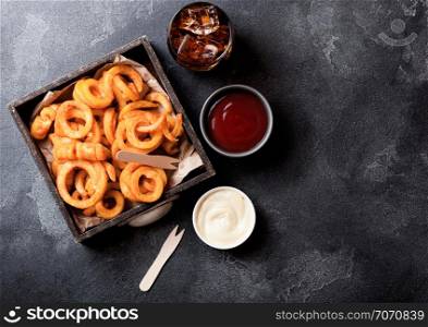 Curly fries fast food snack in wooden box with ketchup and glass of cola on kitchen background. Unhealthy junk food