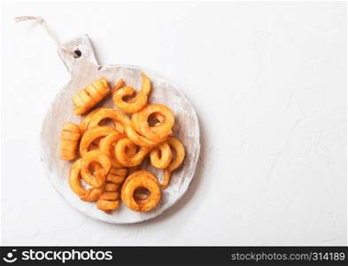 Curly fries fast food snack on wooden board on kitchen background. Unhealthy junk food