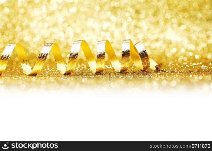 Curly golden gift ribbon on glitters background close-up
