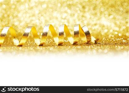 Curly golden gift ribbon on glitters background close-up