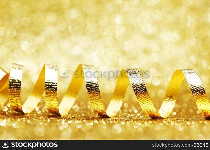 Curly golden serpentine on shiny glitter background, holiday concept