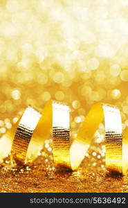 Curly golden serpentine on shiny glitter background, holiday concept