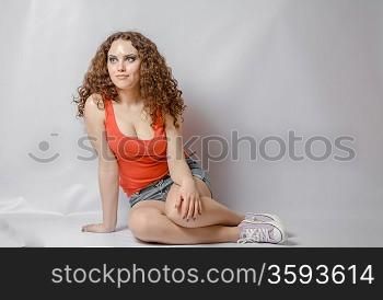 curly hair brunette on white background weared orange red shirt positive girl joy happyness concept sitting