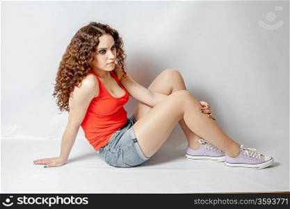 curly hair brunette on white background weared orange red shirt positive girl joy concept sitting side view