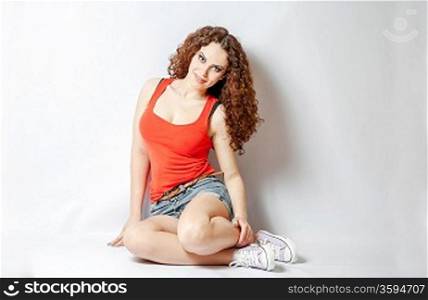 curly hair brunette on white background weared orange red shirt positive girl joy concept sitting