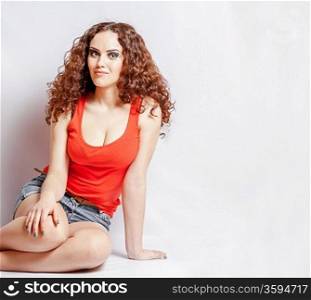 curly hair brunette on white background weared orange red shirt positive girl joy concept sitting