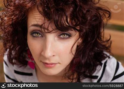 Curly haired female closeup portrait. Red haired women looking at camera