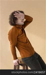 curly haired man with brown blouse posing 2