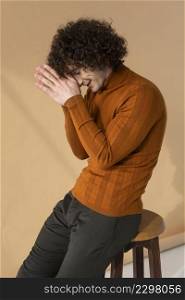curly haired man with brown blouse posing