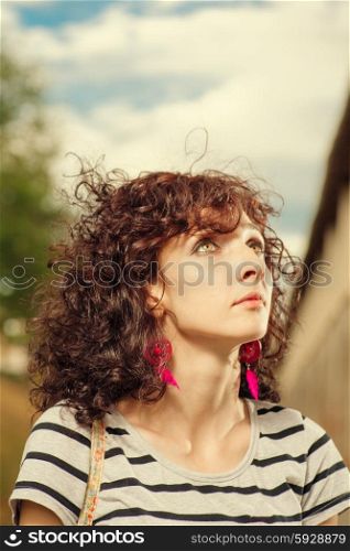Curly haired women looking up. Summer shot of a pretty female outdoors.