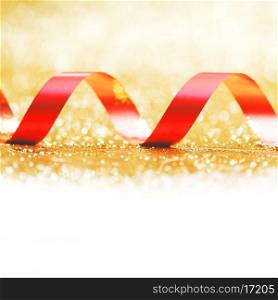 Curly red gift ribbon on glitters background close-up
