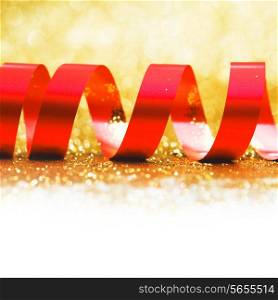 Curly red serpentine on shiny glitter gold background, holiday concept