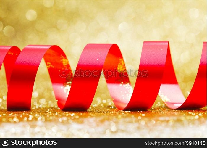 Curly red serpentine on shiny glitter gold background, holiday concept