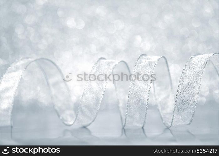 Curly silver Gift ribbon on shiny background close-up