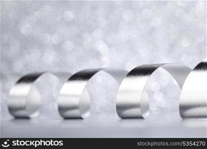 Curly silver Gift ribbon on shiny background close-up