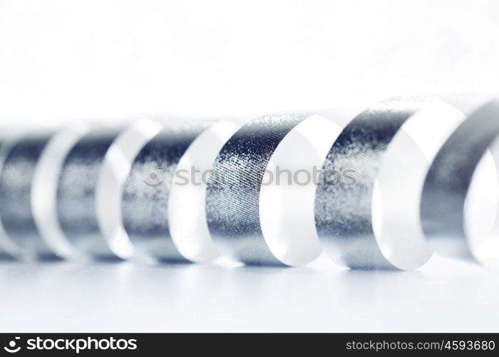 Curly silver serpentine on shiny glitter background, holiday concept