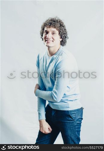 Curly white man in studio posing cheerfully