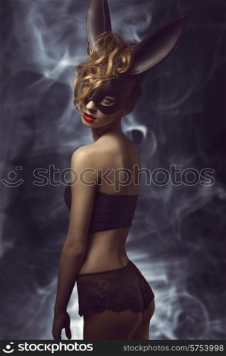 curly woman posing in Easter fashion glamour shoot with black bizarre bunny mask and stylish lace lingerie