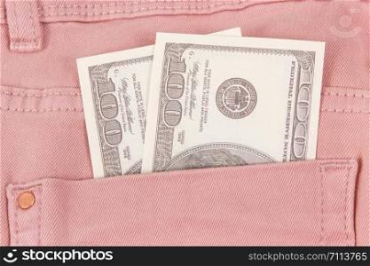 Currencies dollar in pink trousers pocket. Concept of cash payment for shopping. Currencies dollar in trousers pocket. Cash payment for shopping