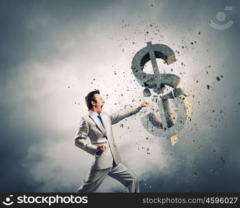 Currency concept. Businessman breaking stone dollar symbol with karate punch