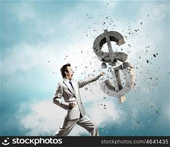 Currency concept. Businessman breaking stone dollar symbol with karate punch