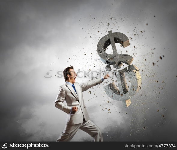 Currency concept. Businessman breaking stone dollar symbol with karate punch