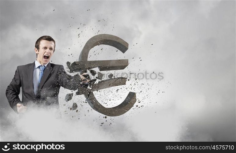 Currency concept. Businessman breaking stone euro symbol with karate punch