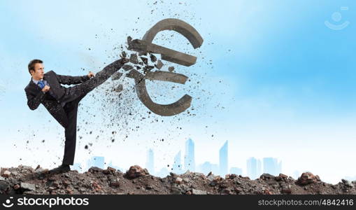 Currency concept. Businessman breaking stone euro symbol with karate punch