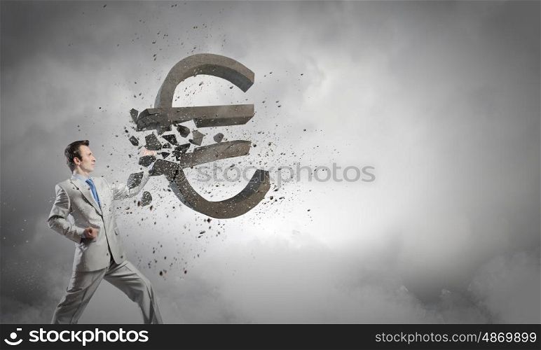 Currency concept. Businessman breaking stone euro symbol with karate punch