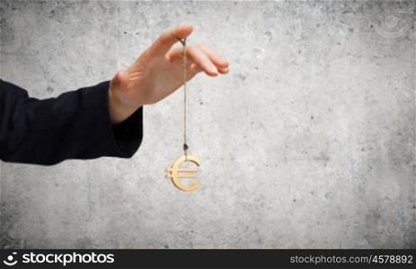 Currency concept. Close up of businessman hand and euro sign hanging on finger