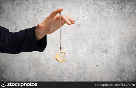 Currency concept. Close up of businessman hand and euro sign hanging on finger