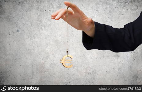 Currency concept. Close up of businessman hand and euro sign hanging on finger