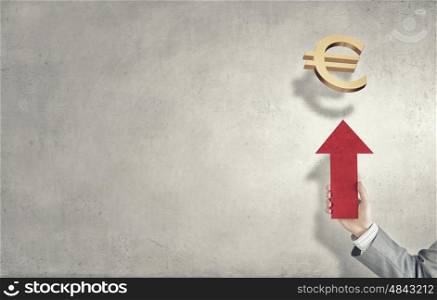 Currency concept. Hand of businessman holding arrow and pointing at euro sign