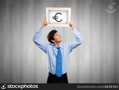 Currency concept. Handsome man holding frame with euro sign
