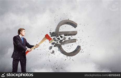 Currency concept. Young businessman breaking dollar stone sign with axe