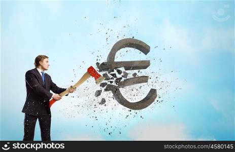 Currency concept. Young determined businessman crashing euro sign with axe