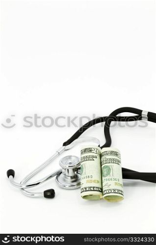 Currency leans against a stethoscope in image with vertical orientation and copy space