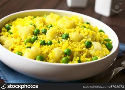 Curried couscous with peas, cauliflower, ginger and garlic, photographed with natural light (Selective Focus, Focus in the middle of the dish)