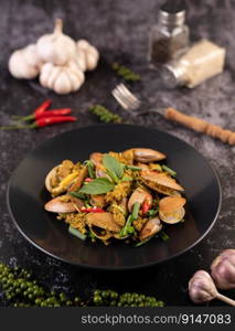 Curry powder stir fry on a black plate along with garlic. Chili and basil.