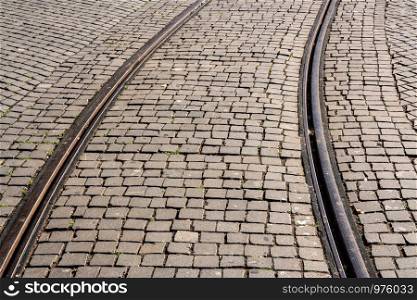 Curve of steel rails from tramcar track set into stone cobble pattern in Porto. Steel rails set in granite cobblestone road in Porto