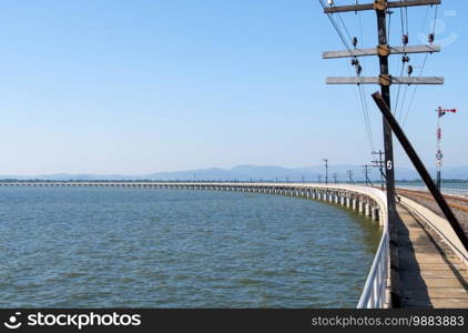 Curved concrete bridge of the railway line along the reservoir with the traffic signal pole, central line in Thailand.