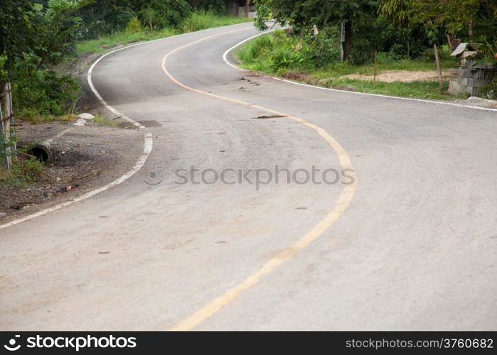 Curved road is curved, not much. The side of the road with a tree.