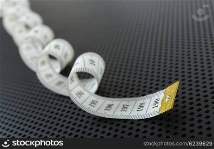 Curved white measuring tape on black background perforated
