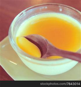 Custard pudding and wooden spoon with retro filter effect