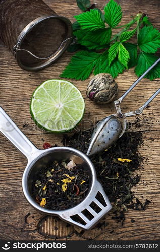 custard the strainer with spoon and spilled tea brewing. tea brew with lime and mint on wooden background