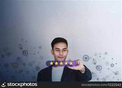 Customer Experience Concept. Young Businessman with Happy Face Showing Five Star Services Rating Satisfaction on Card. Happy Client&rsquo;s Feedback and Online Review. Surrounded by Network Icons